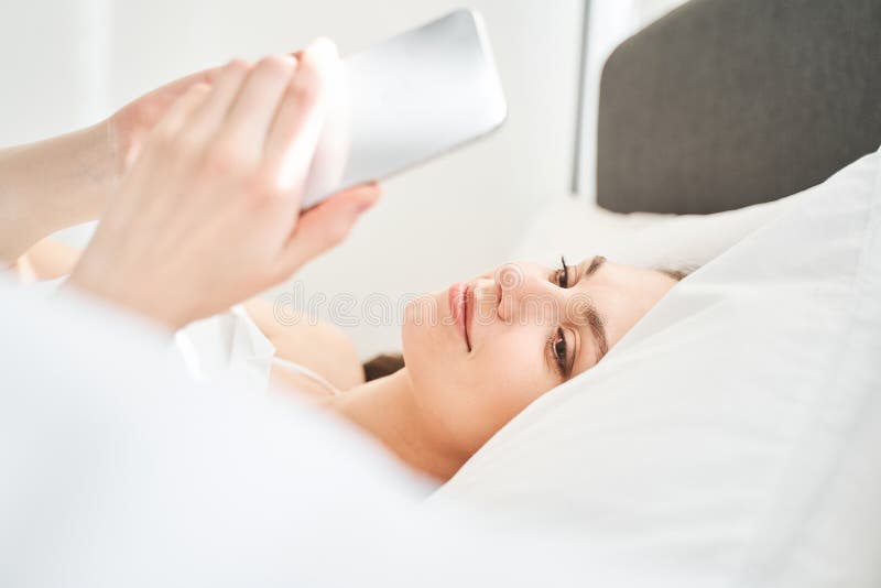 Flicka med en gadget i sovrummet royaltyfri fotografi