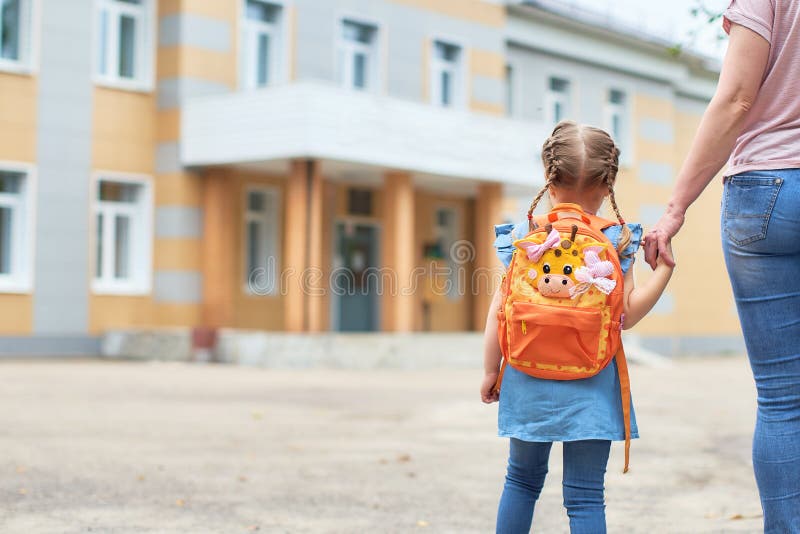 Flicka med portföljer nära skolan arkivfoto Flicka med portföljer nära skolan arkivfoto