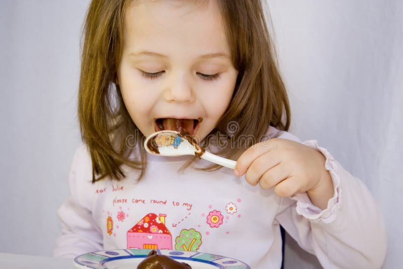 Flicka och chokladen. Liten flicka som äter chokladen