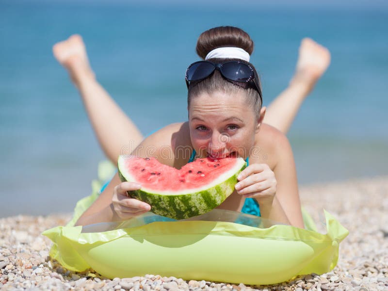 Girl at the sea. Young woman eats watermelon on seashore. Girl at the sea. Young woman eats watermelon on seashore