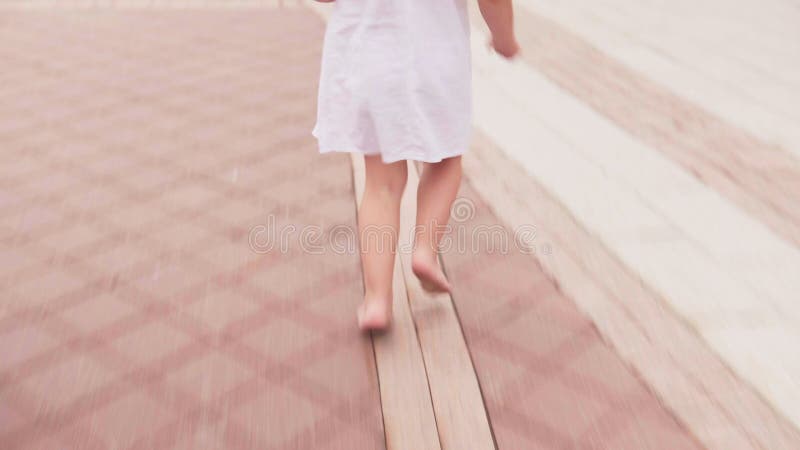 Flicka som barfota kör på stadsgatan i den vita klänningen