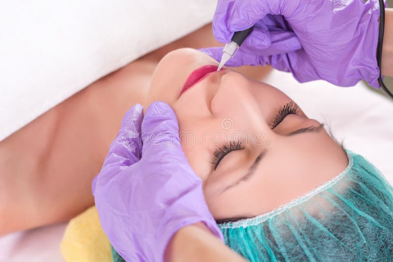 Flicka som har permanent makeup på kanter i kosmetologsalong arkivbild Flicka som har permanent makeup på kanter i kosmetologsalong arkivbild