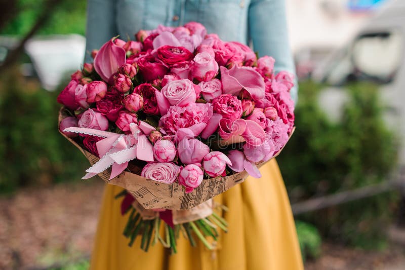 Flicka som rymmer en bukett av rosa blommor arkivbild