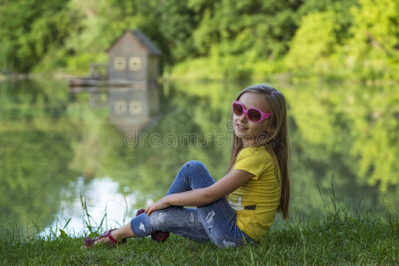 Flicka som sitter utanför på en solig dag Liten flicka som sitter i sommarskogen royaltyfri bild Flicka som sitter utanför på en solig dag Liten flicka som sitter i sommarskogen royaltyfri bild