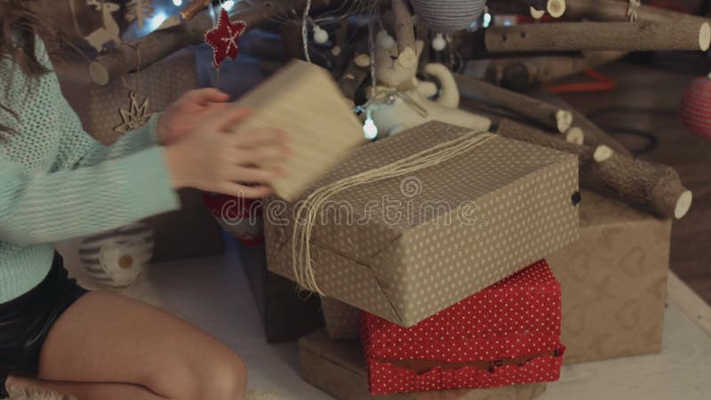 Flicka som sätter emballerade gåvor under julträträdet