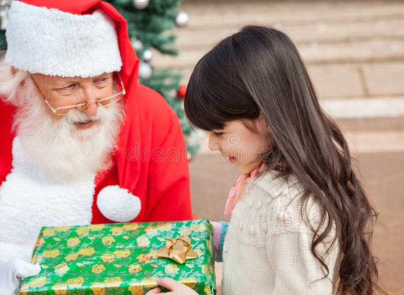 Flicka som tar julgåvan från Santa Claus arkivfoton Flicka som tar julgåvan från Santa Claus arkivfoton