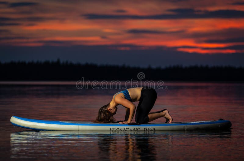 Flicka som övar yoga på paddleboard i solnedgången på den sceniska sjön Velke Darko royaltyfri fotografi Flicka som övar yoga på paddleboard i solnedgången på den sceniska sjön Velke Darko royaltyfri fotografi