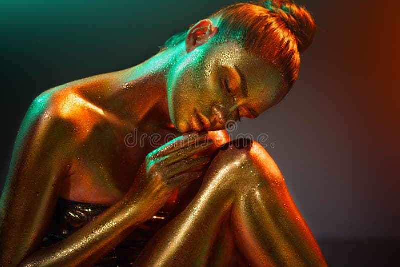 Flickan för modemodellen i färgrikt ljust guld- mousserar på hennes kropp i neonljus som poserar, flicka med glödande makeup fotografering för bildbyråer