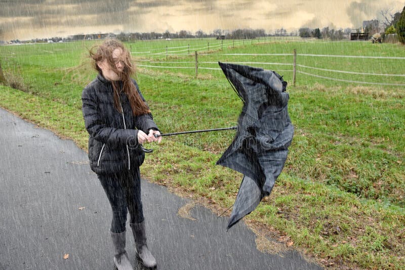 Stormy weather, teenage girl walks outside in the rain fighting with her broken umbrella. Stormy weather, teenage girl walks outside in the rain fighting with her broken umbrella.