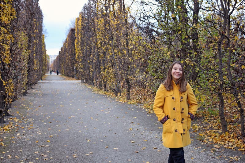 Flickan i gula rocken som går i parken hösten royaltyfri foto