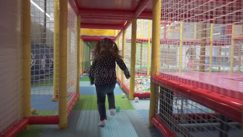 Flickan kör till och med tunnelen i barns labyrint på lekplats