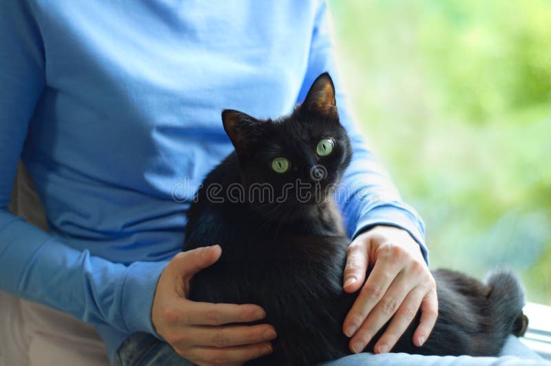Flickan rymmer en svart katt arkivbild Flickan rymmer en svart katt arkivbild