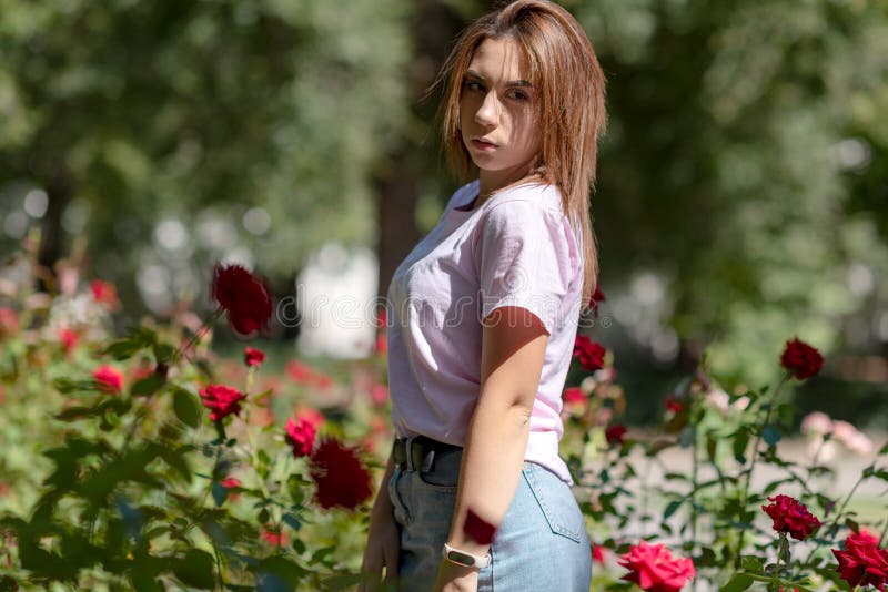 Flickan sniffar en röd blomma tonåringflicka som luktar rosor arkivfoto Flickan sniffar en röd blomma tonåringflicka som luktar rosor arkivfoto