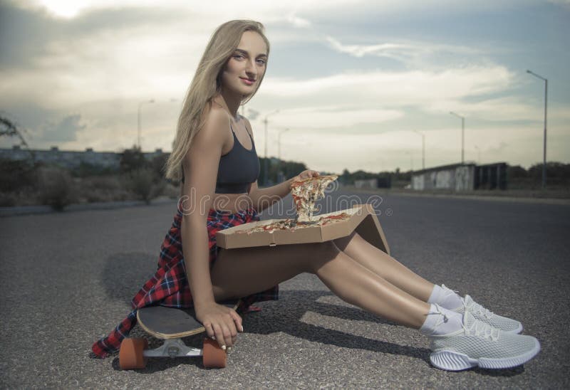 Flickan som hoppar av en skateboard med den headphonesGirlvarken skateboarden eller longboard, levererar pizza i staden royaltyfria foton Flickan som hoppar av en skateboard med den headphonesGirlvarken skateboarden eller longboard, levererar pizza i staden royaltyfria foton