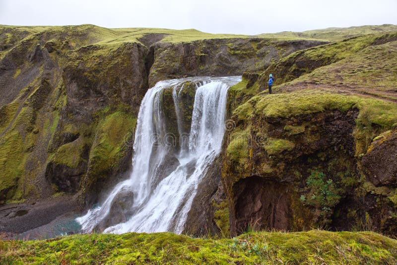 Flickan står på kanten av klyftan på vattenfallet Fagrifoss royaltyfri foto Flickan står på kanten av klyftan på vattenfallet Fagrifoss royaltyfri foto
