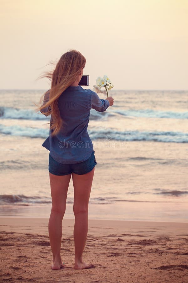 Flickan tar bilder av Plumeriablomman royaltyfri fotografi Flickan tar bilder av Plumeriablomman royaltyfri fotografi