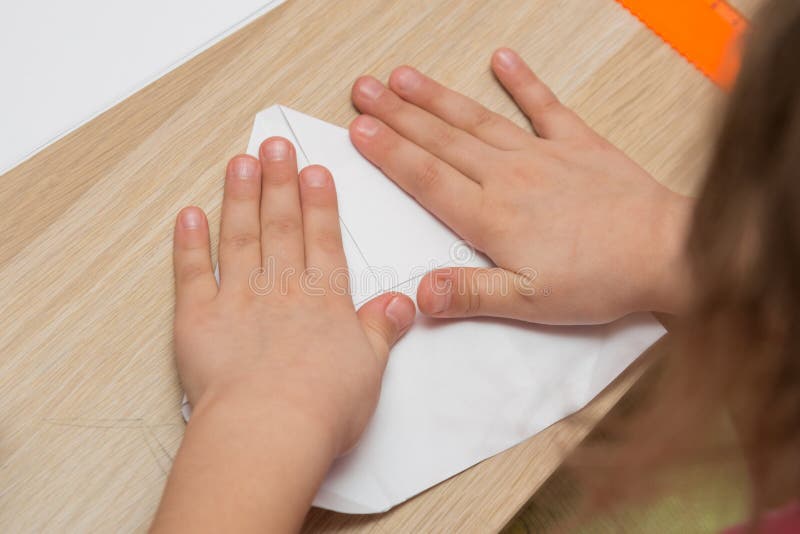 Flickan är förlovad i origami, gör det pappers- flygplanet royaltyfri fotografi Flickan är förlovad i origami, gör det pappers- flygplanet royaltyfri fotografi