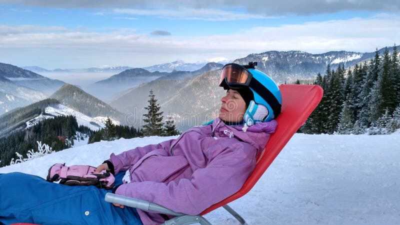 Flickasnowboarderen vilar på lutningen av ett snöig berg royaltyfria foton