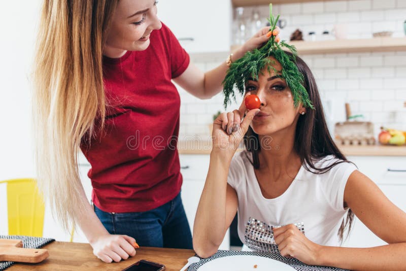 Flickor som omkring bedrar i k?ket som spelar med gr?nsaker arkivfoto Flickor som omkring bedrar i k?ket som spelar med gr?nsaker arkivfoto