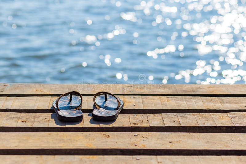 Flip Flops auf dem Holzsteg und Landschaft des Sees im natürlichen Hintergrund lizenzfreie stockfotos Flip Flops auf dem Holzsteg und Landschaft des Sees im natürlichen Hintergrund lizenzfreie stockfotos