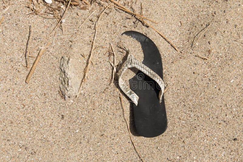 Flip flop lying on the beach thus causing environmental pollution. Flip flop lying on the beach thus causing environmental pollution