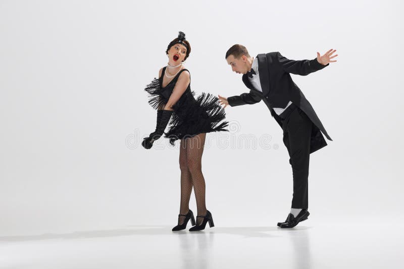 Flirty mood, men and women in vintage attire engaged in lively dance isolated over white studio background. Roaring twenties. Concept of art, retro and vintage, hobby, entertainment, 20s. Flirty mood, men and women in vintage attire engaged in lively dance isolated over white studio background. Roaring twenties. Concept of art, retro and vintage, hobby, entertainment, 20s