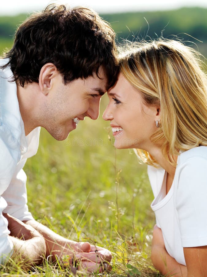 Flirting couple lying in green meadow