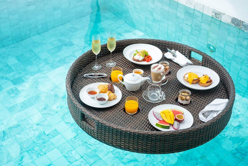 Floating Breakfast tray in swimming pool at luxury hotel or tropical resort villa, fruits; mango, watermelon dragon and passion fruit, food, bread, coffee, tea, wine and orange juice. Exotic summer. Floating Breakfast tray in swimming pool at luxury hotel or tropical resort villa, fruits; mango, watermelon dragon and passion fruit, food, bread, coffee, tea, wine and orange juice. Exotic summer