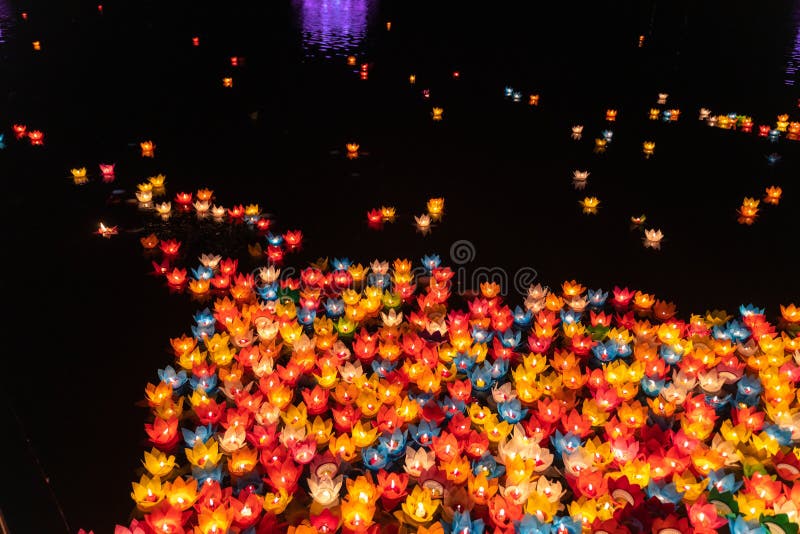 Floating colored lanterns and garlands on river at night on Vesak day for celebrating Buddha's birthday in Eastern culture, that made from paper and candle