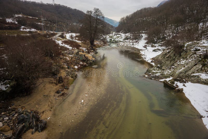 Flod med gräsplanvatten, snö och is nära Xanthi i Grekland