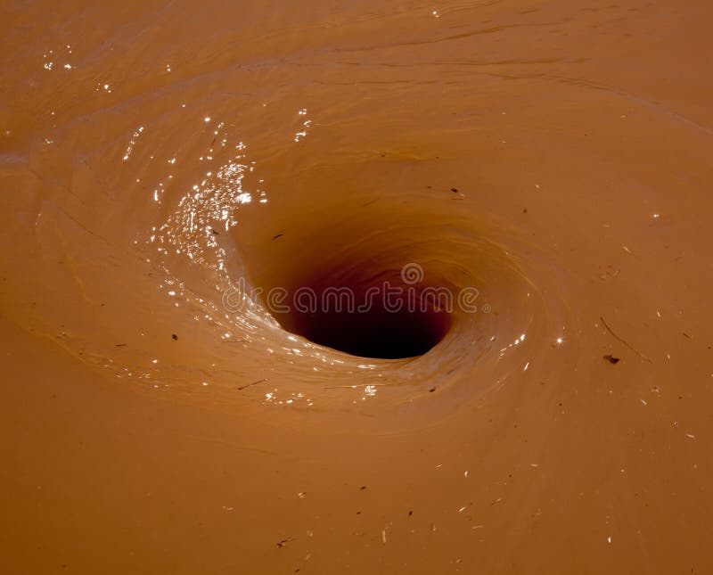 Deep brown flood water in river swirling into a whirlpool. Whirlpool vortex water stock images, royalty-free photos and pictures