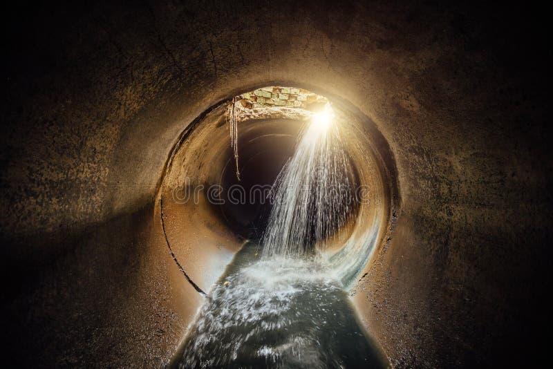 Flooded round sewer tunnel with water reflection