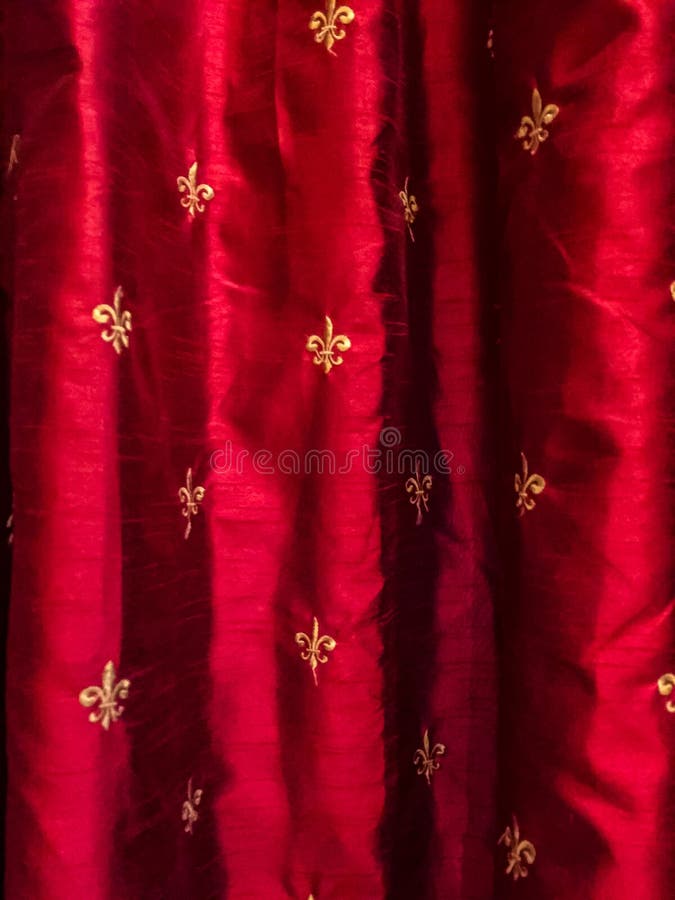 Flor de lis do ouro em cortinas de seda vermelhas fotografia de stock Flor de lis do ouro em cortinas de seda vermelhas fotografia de stock