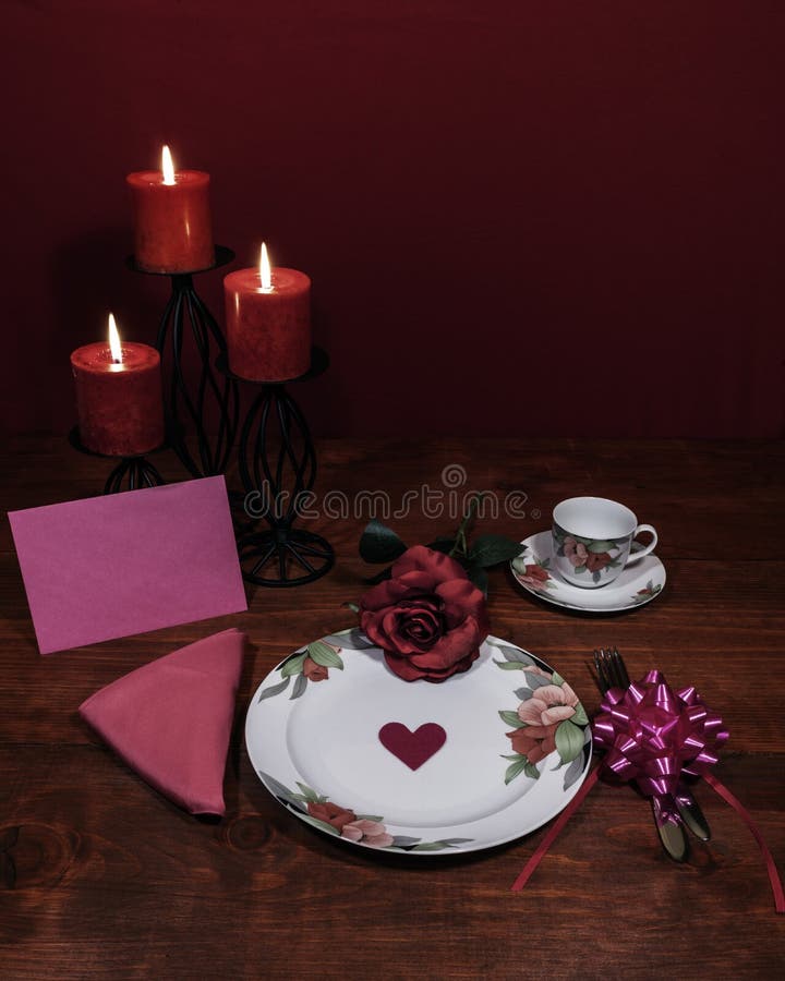 Floral pattern china dinnerware. pink rose, pink napkin and bow, silverware, red candles and pink card