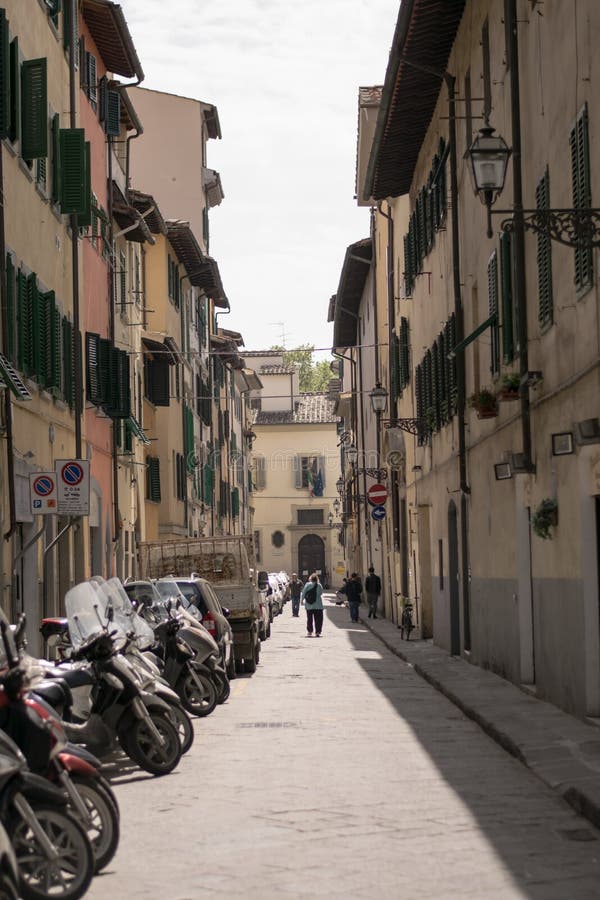 Florence Italien - 24 April, 2018: en gammal gata med parkerade cyklar och några personer arkivbild Florence Italien - 24 April, 2018: en gammal gata med parkerade cyklar och några personer arkivbild