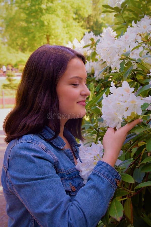 Flores blancas el oler de la mujer joven en el parque imagen de archivo Flores blancas el oler de la mujer joven en el parque imagen de archivo