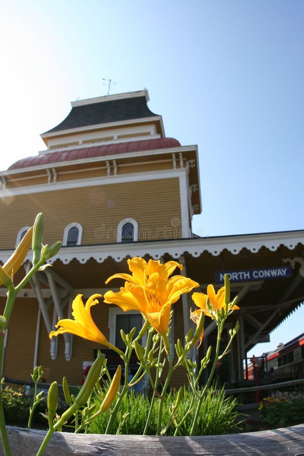 Flores na frente de um estação de caminhos de ferro em Conway norte, New Hampshire fotografia de stock Flores na frente de um estação de caminhos de ferro em Conway norte, New Hampshire fotografia de stock