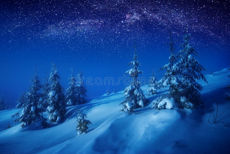 The valley covered with fresh snow in a moonlight. Milky way in a starry sky. Christmas and New Year winter night. The valley covered with fresh snow in a moonlight. Milky way in a starry sky. Christmas and New Year winter night.