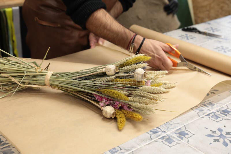 Florist packs a bouquet of beautiful dried flowers plants - chrysanthemums, lavender, poppies, wheat spikelets in the greek flower