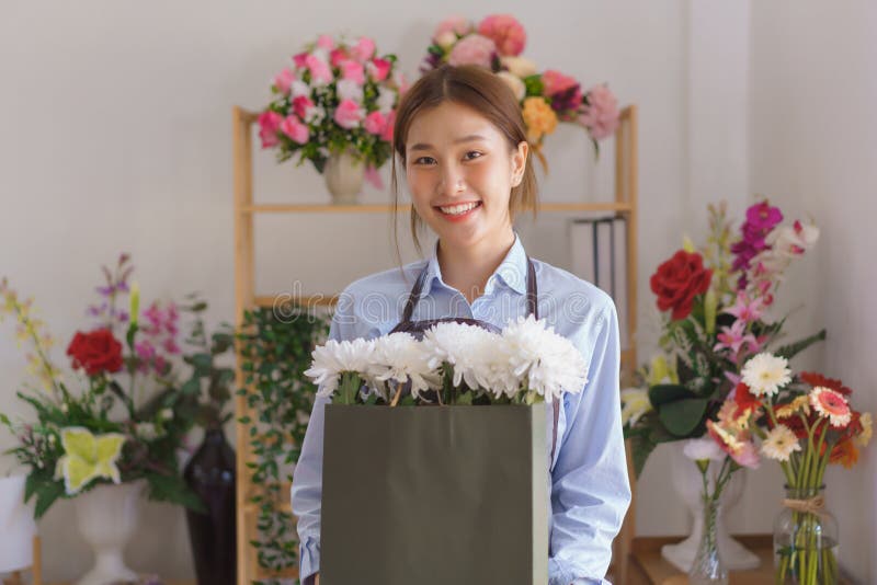 Florista donna che tiene in ostaggio il crisantemo bianco bouquet in un sacchetto di carta in un negozio di fiori immagine stock libera da diritti