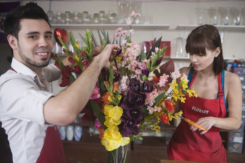 Portrait of male florist working with female colleague in flower shop. Portrait of male florist working with female colleague in flower shop