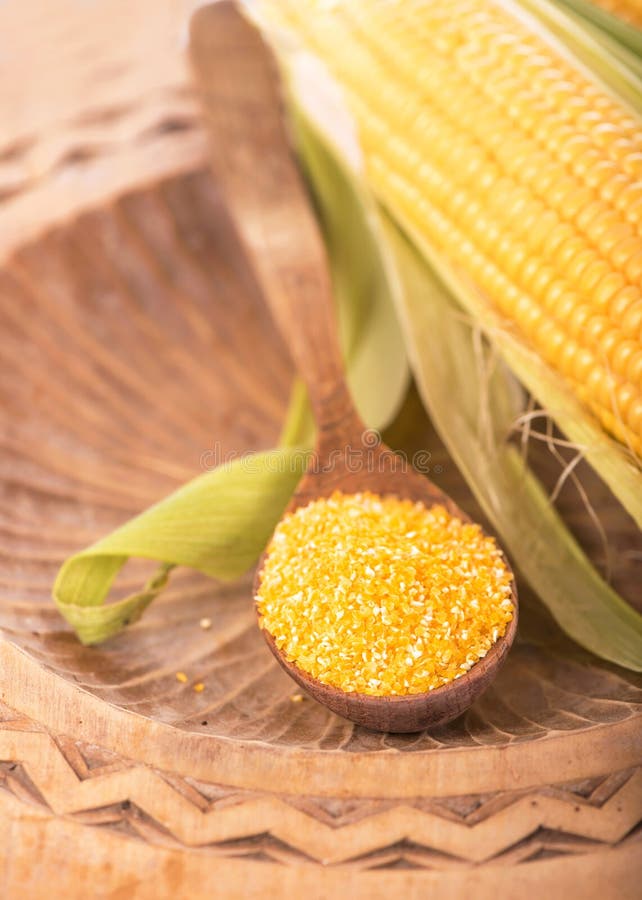 Flour corn in a spoon on the dark wooden boards