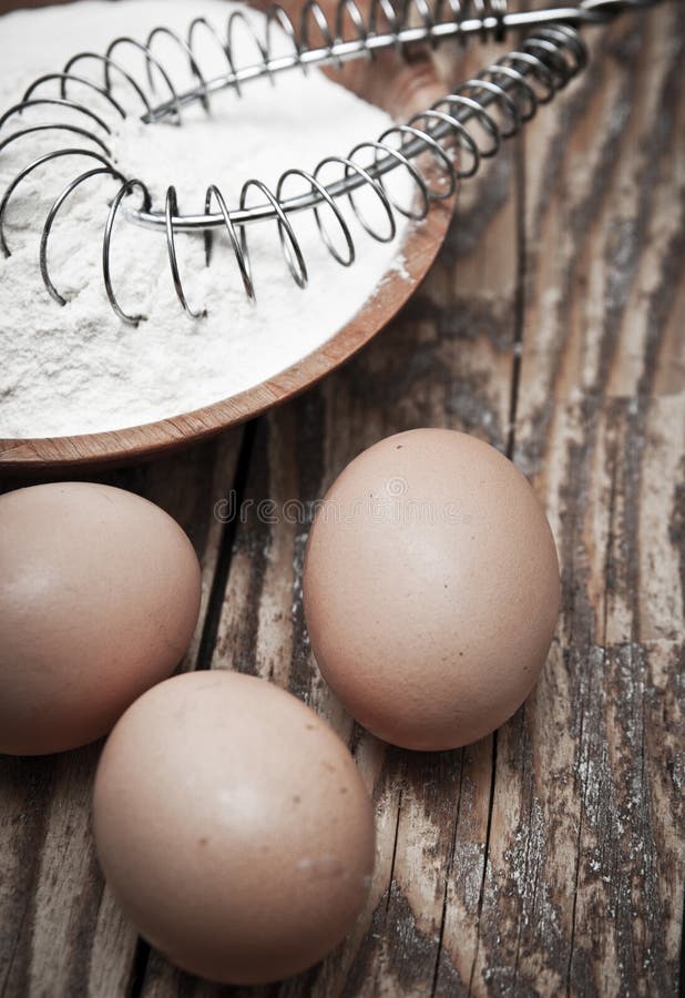 Flour and eggs on wooden background