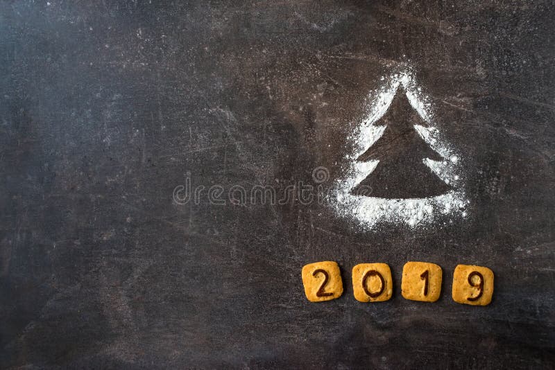 Flour l'arbre de Noël de silhouette avec les chiffres 2019 de biscuits sur l'obscurité image libre de droits Flour l'arbre de Noël de silhouette avec les chiffres 2019 de biscuits sur l'obscurité image libre de droits