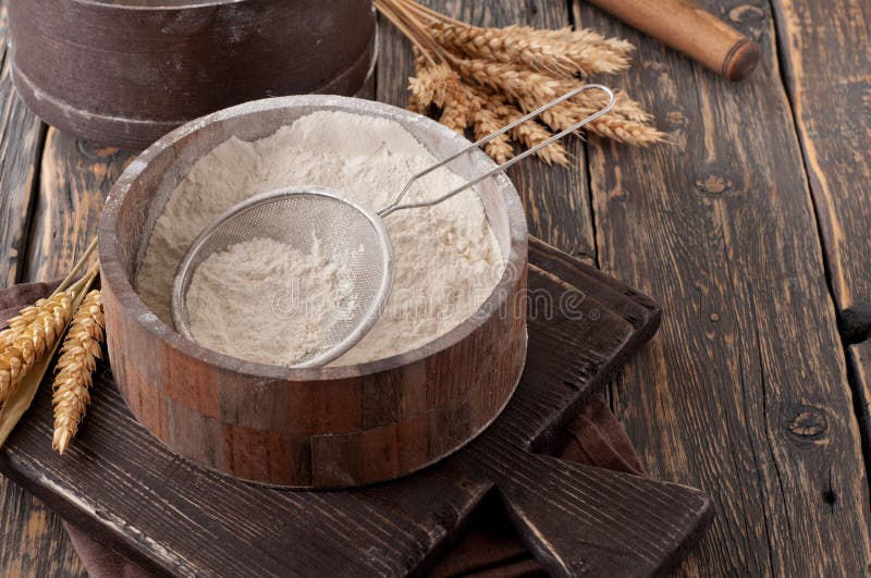 Flour in a wooden bowl with sieve on vintage board royalty free stock photos Flour in a wooden bowl with sieve on vintage board royalty free stock photos