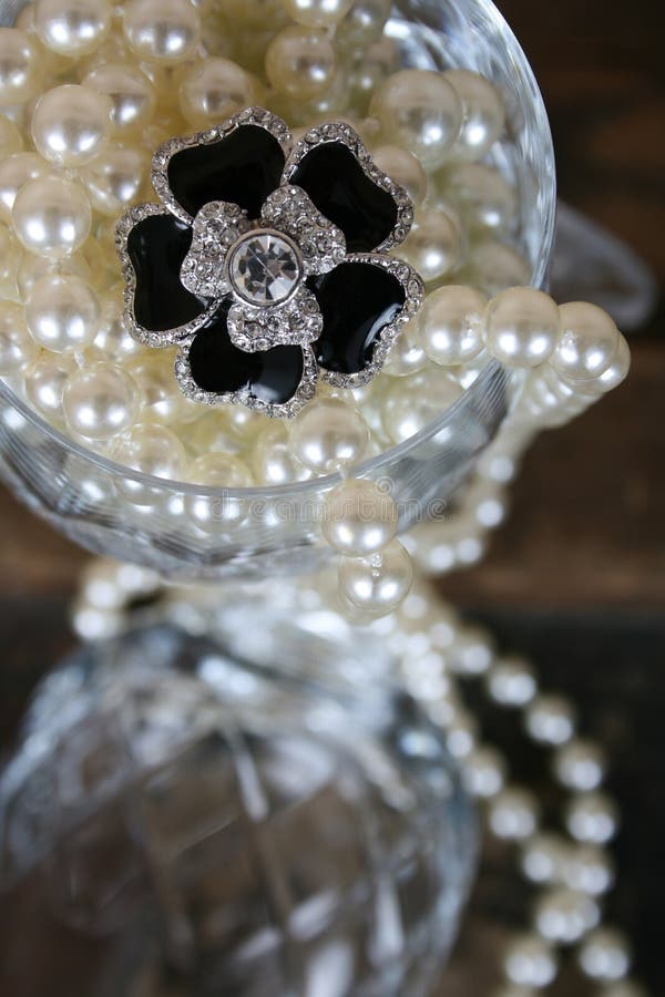 Black flower diamond ring amongst pearls in crystal glass