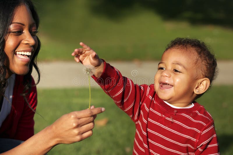 Mother and son playing with a dandelion in the park. Mother and son playing with a dandelion in the park