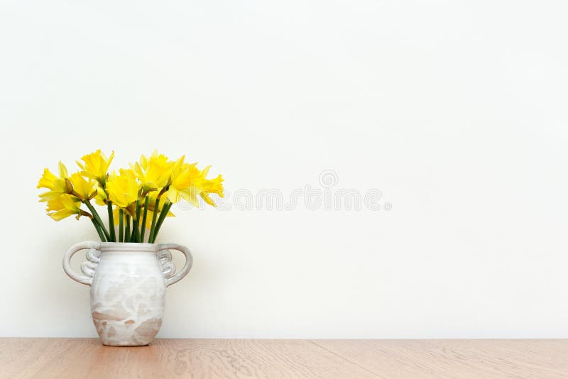 Flowers in a rustic style vase on wooden table with white interior wall background, daffodils stock images Flowers in a rustic style vase on wooden table with white interior wall background, daffodils stock images