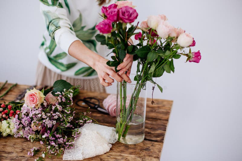 Beautiful flowers pink and white in a vase on a wooden table in a bright room. The girl florist makes a bouquet. Beautiful flowers pink and white in a vase on a wooden table in a bright room. The girl florist makes a bouquet.