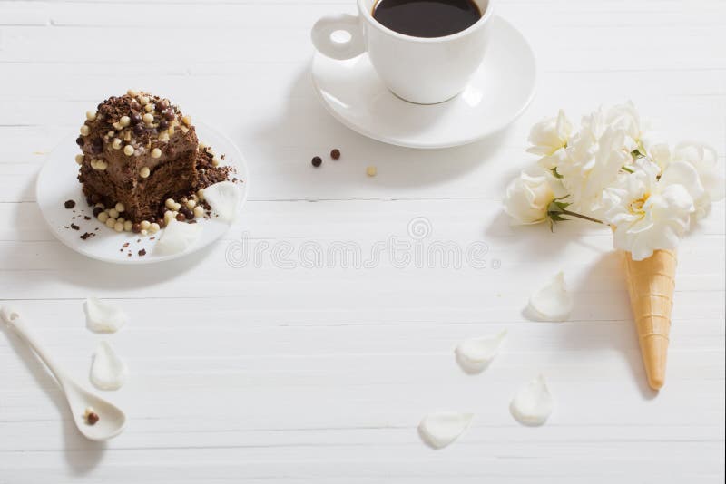 Flowers in waffle cone and chocolate cake on wooden backg
